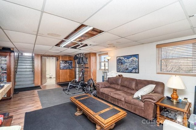 living area with light wood-style flooring, a drop ceiling, and stairway