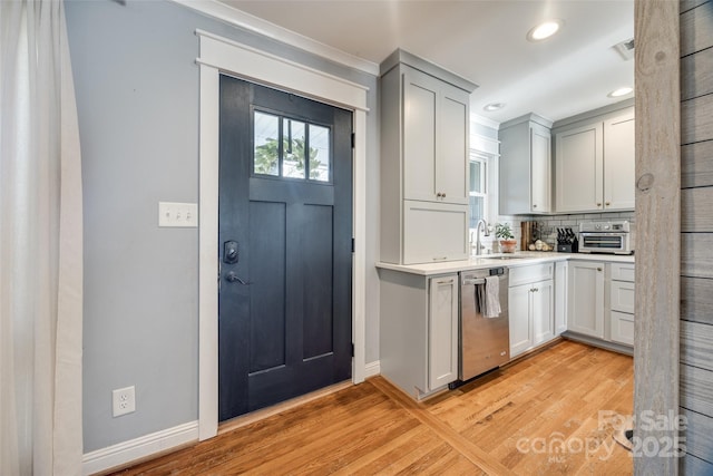 kitchen with tasteful backsplash, dishwasher, sink, and light wood-type flooring