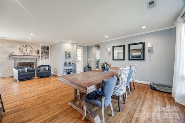 dining area featuring crown molding, light hardwood / wood-style floors, and a brick fireplace