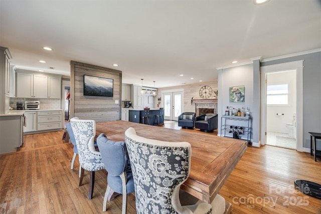 dining area featuring ornamental molding, light wood-type flooring, and french doors