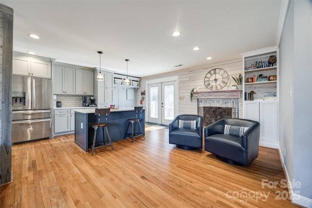 kitchen with stainless steel fridge with ice dispenser, a fireplace, light hardwood / wood-style floors, and french doors