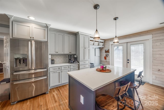 kitchen featuring a kitchen island, pendant lighting, a breakfast bar area, stainless steel fridge, and light wood-type flooring