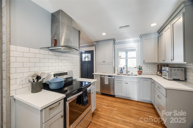 kitchen with sink, stainless steel appliances, tasteful backsplash, exhaust hood, and light wood-type flooring