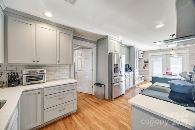 kitchen featuring gray cabinets, tasteful backsplash, light hardwood / wood-style floors, stainless steel fridge with ice dispenser, and decorative light fixtures