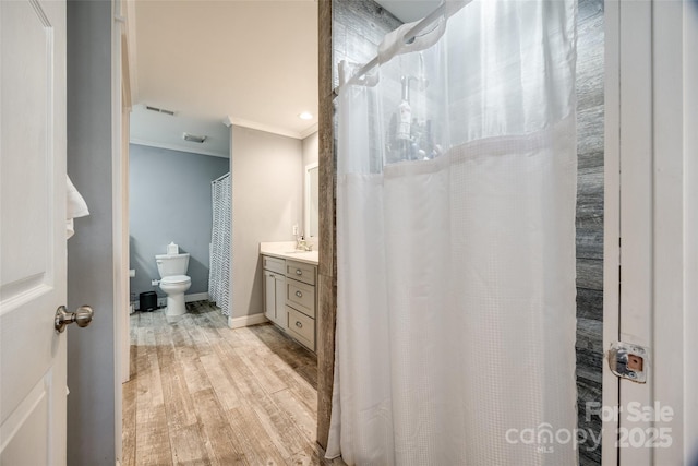 bathroom featuring vanity, hardwood / wood-style floors, crown molding, and toilet