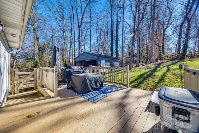 wooden terrace with a garage, a yard, and an outbuilding