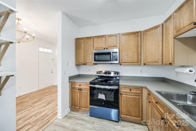 11426 Savannah Creek Dr, Charlotte, NC 28273 - kitchen featuring a chandelier, a textured ceiling, stainless steel appliances, a sink, and light wood finished floors