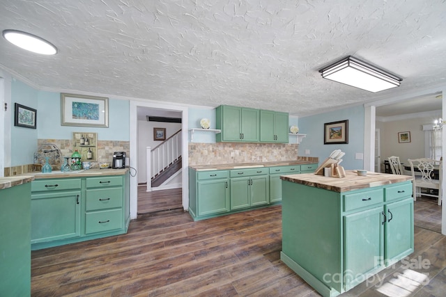 kitchen featuring dark wood-type flooring, a kitchen island, decorative backsplash, green cabinets, and wooden counters