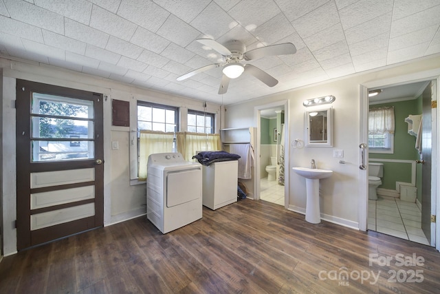 clothes washing area featuring sink, ceiling fan, washing machine and clothes dryer, crown molding, and dark hardwood / wood-style floors