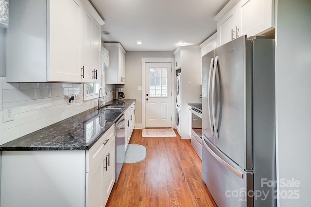 kitchen with sink, white cabinetry, light hardwood / wood-style flooring, stainless steel appliances, and decorative backsplash