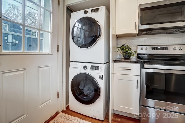 laundry room featuring stacked washer / dryer and light wood-type flooring