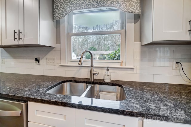 kitchen with sink, white cabinetry, decorative backsplash, stainless steel dishwasher, and dark stone counters