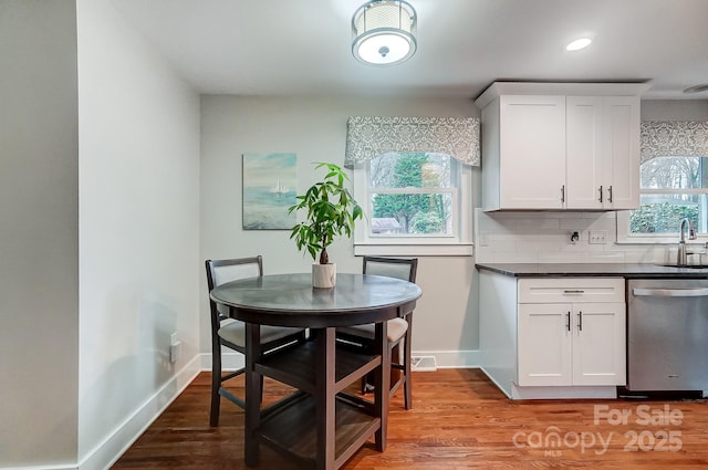 kitchen featuring white cabinetry, stainless steel dishwasher, sink, and backsplash