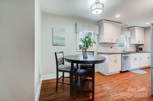 kitchen featuring dishwasher, light hardwood / wood-style flooring, white cabinets, and decorative backsplash