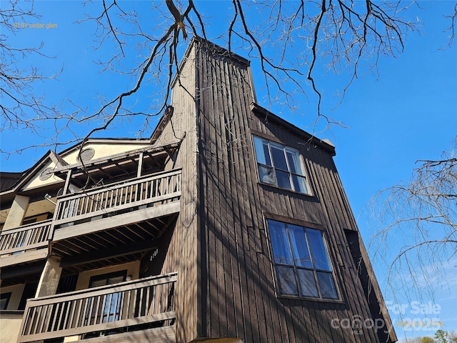 view of property exterior with a balcony and a chimney