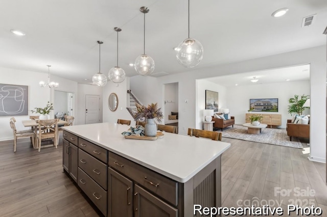 kitchen with dark brown cabinetry, pendant lighting, and light hardwood / wood-style floors