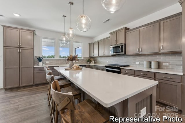 kitchen with electric stove, pendant lighting, a breakfast bar, and a kitchen island