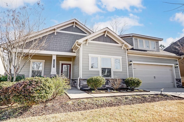 craftsman-style home with a garage, driveway, board and batten siding, and stone siding