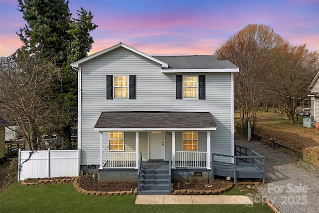 view of property featuring a porch and a lawn