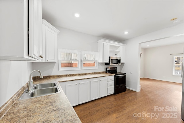 kitchen with white cabinetry, sink, hardwood / wood-style floors, and electric range