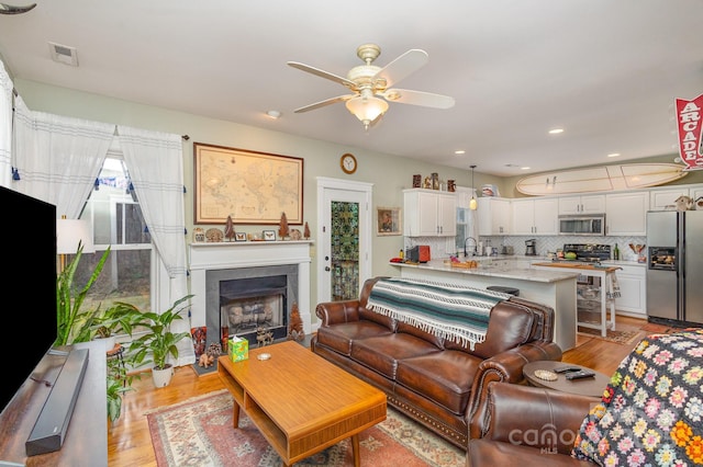 living room with a fireplace, recessed lighting, visible vents, light wood-style floors, and a ceiling fan