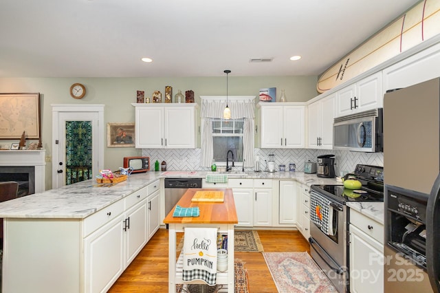 kitchen featuring stainless steel appliances, visible vents, white cabinetry, a center island, and pendant lighting