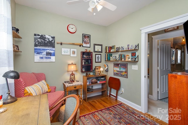 living area featuring ceiling fan, wood finished floors, and baseboards