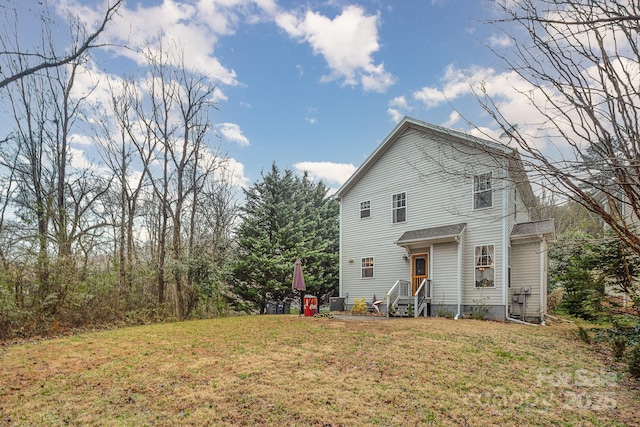 rear view of property featuring entry steps and a yard