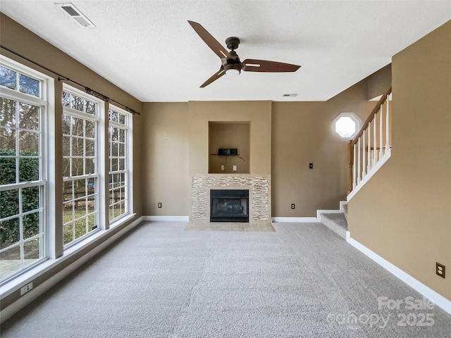 unfurnished living room with visible vents, a tiled fireplace, baseboards, and stairs