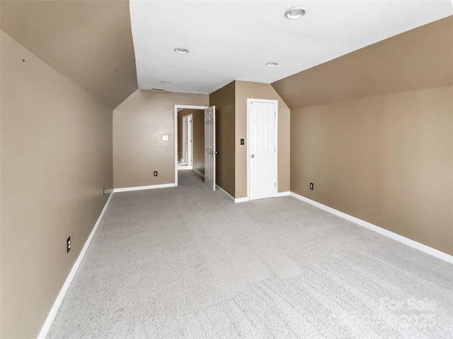 additional living space with lofted ceiling, light colored carpet, and baseboards