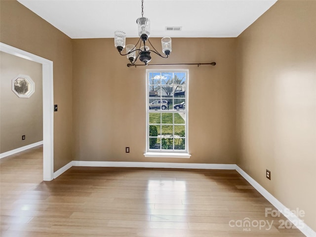 unfurnished dining area with baseboards, light wood finished floors, visible vents, and a notable chandelier