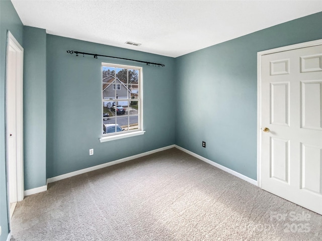 empty room featuring carpet, visible vents, and baseboards