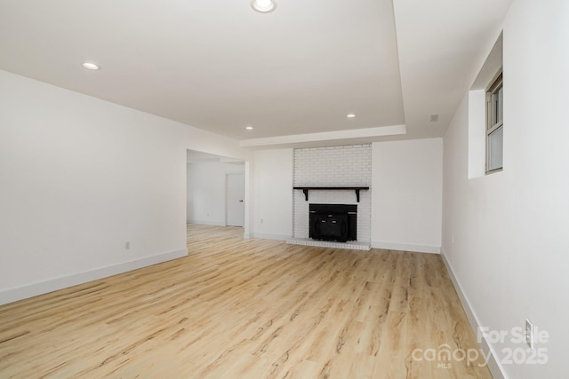 unfurnished living room with baseboards, recessed lighting, a fireplace, and light wood finished floors