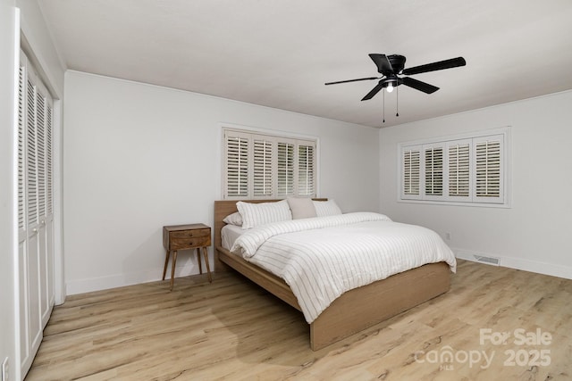 bedroom featuring a closet, baseboards, visible vents, ceiling fan, and light wood finished floors