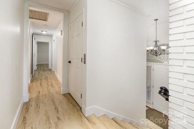 hallway with visible vents, light wood-style flooring, a notable chandelier, and baseboards