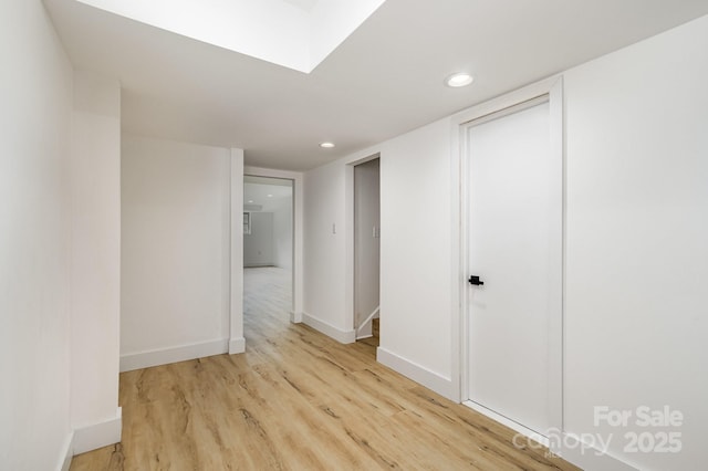 corridor featuring recessed lighting, light wood-style flooring, and baseboards