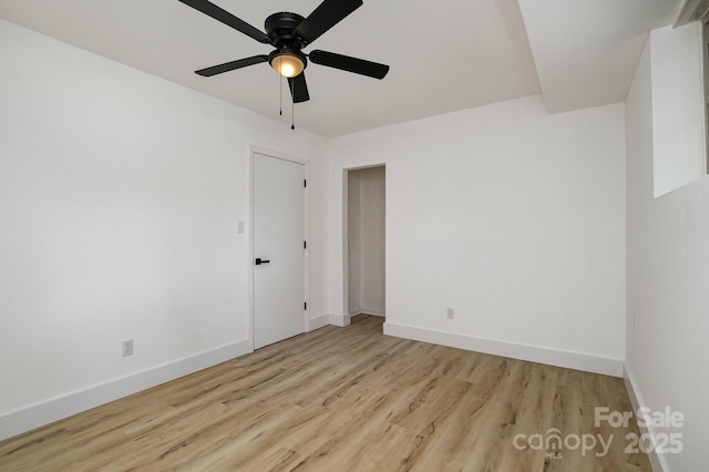 empty room featuring ceiling fan, baseboards, and wood finished floors