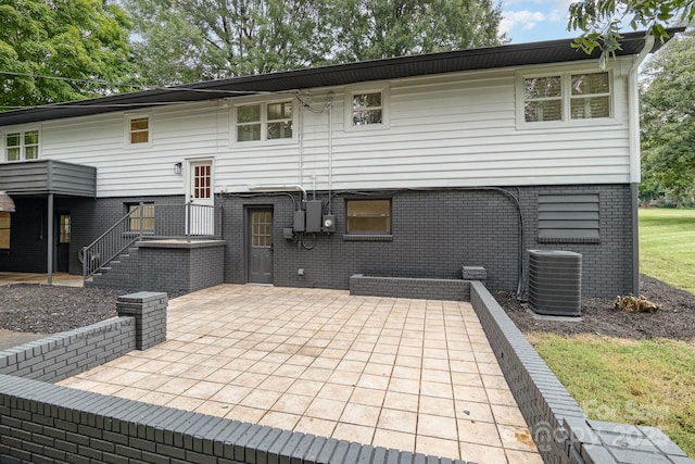 rear view of property with a patio, brick siding, and central AC