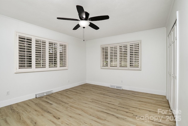 unfurnished room with visible vents, ceiling fan, baseboards, and wood finished floors