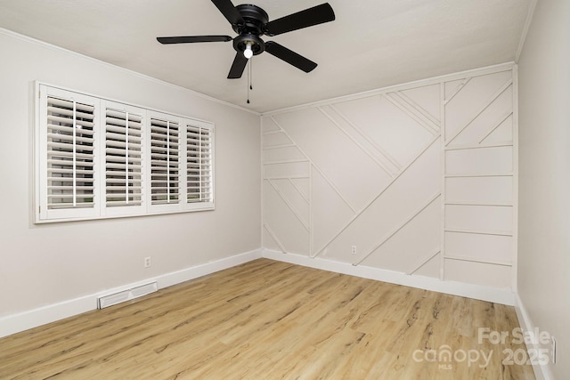 empty room with ceiling fan, ornamental molding, visible vents, wood finished floors, and baseboards