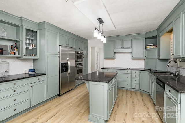 kitchen with a sink, open shelves, green cabinetry, and stainless steel appliances