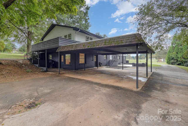 view of parking / parking lot with an attached carport, stairway, and driveway