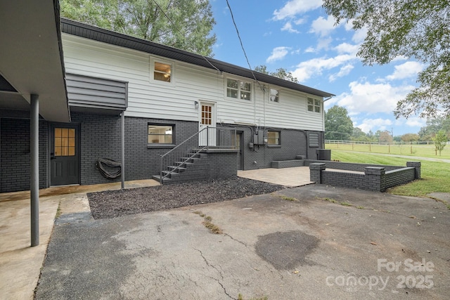 rear view of property featuring central AC unit, fence, brick siding, and a patio area