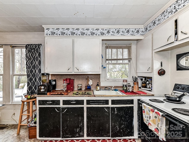 kitchen featuring ornamental molding, sink, white cabinets, and electric stove