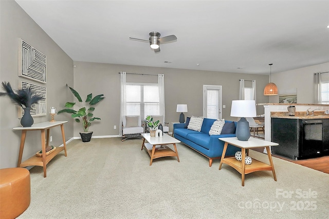 living area with carpet floors, baseboards, and a ceiling fan