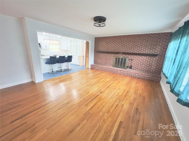 108 Meadowview Pl, Lenoir, NC 28645 - unfurnished living room with wood finished floors, a fireplace, baseboards, and brick wall