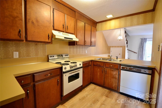 kitchen with sink, hanging light fixtures, white appliances, a textured ceiling, and light hardwood / wood-style flooring