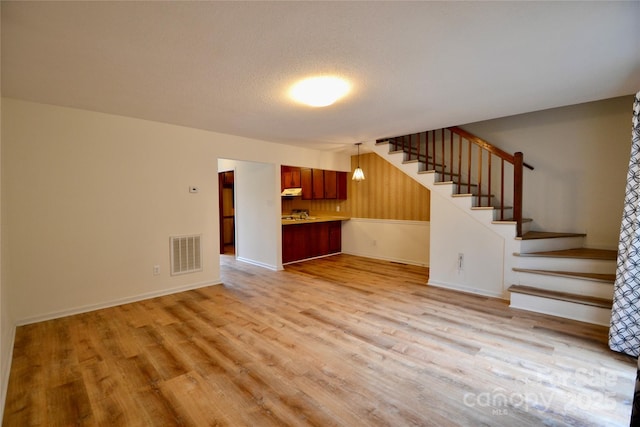 unfurnished living room featuring light hardwood / wood-style flooring and a textured ceiling