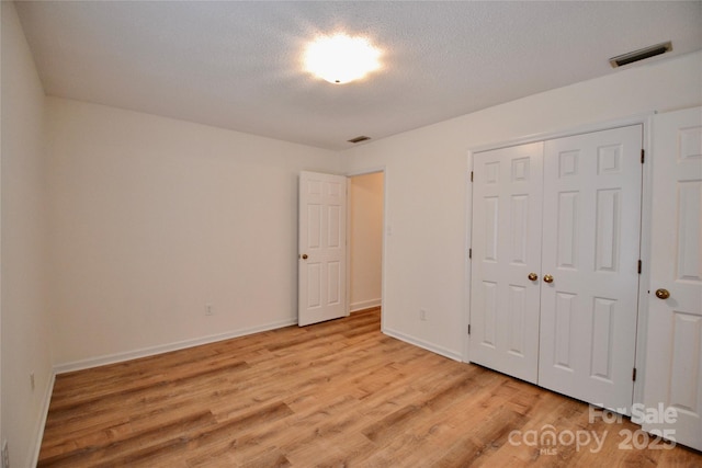 unfurnished bedroom with a closet, light hardwood / wood-style floors, and a textured ceiling