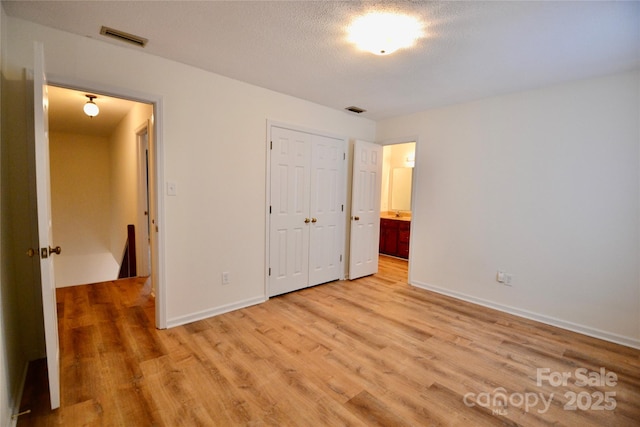 unfurnished bedroom featuring a textured ceiling, a closet, and light wood-type flooring